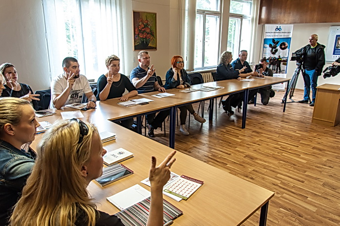 Dziennikarze i fotoreporterzy uczestniczą w warsztatach polskiego języka migowego realizowanych w ramach projektu „Bezpieczni Obywatele Świata Ciszy”. Policjanci prezentują umiejętności zdobyte w trakcie poprzednich zajęć.